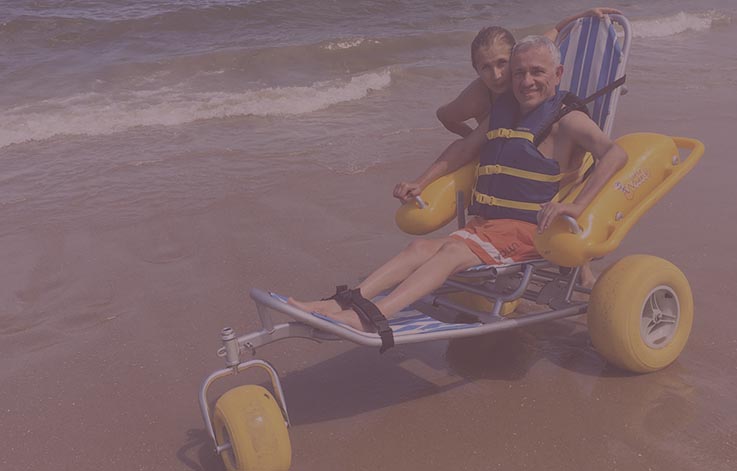 Persona en playa montada en silla de ruedas náutica 
